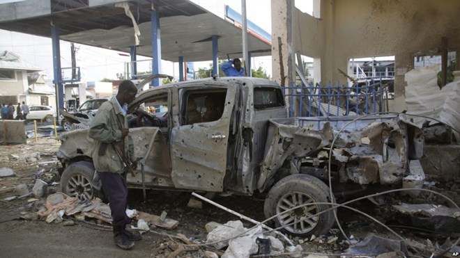 A Somali security man looks at the wreckage of a truck near the Nasahablood hotel in Mogadishu, Somalia, June 26, 2016. The Islamic extremist group al-Shabab claimed responsibility for the damage, inflicted in an attack the day before.